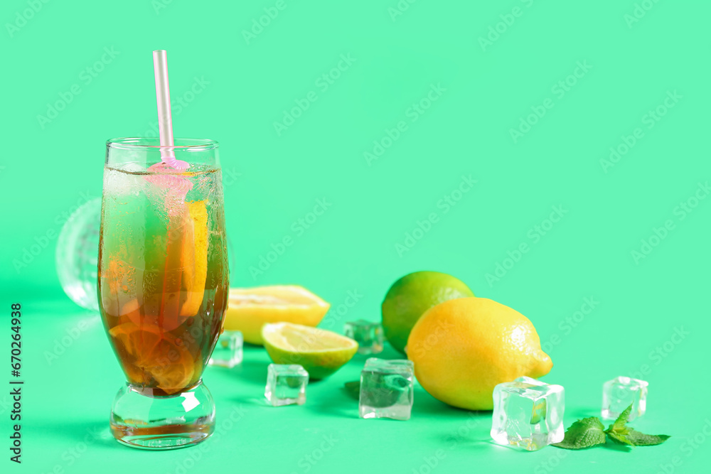 Glass of tasty Long Island iced tea, citrus fruits and mint leaves on color background