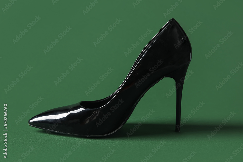 Stylish black high heel on green background