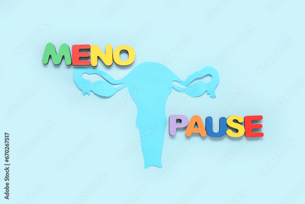 Word MENOPAUSE with paper uterus on blue background