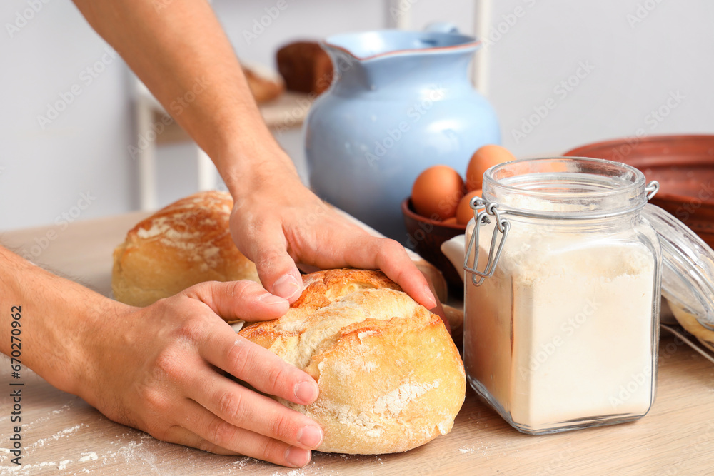 Young man with loaves of fresh bread in bakery