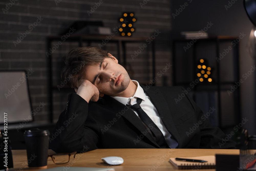 Sleeping young man working in office at night