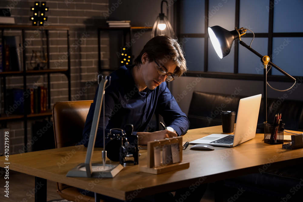 Young businessman writing in notebook at office