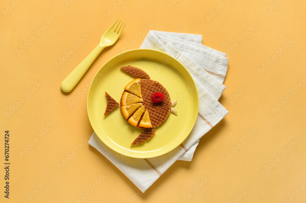 Plate with funny childrens breakfast in shape of fish on orange background