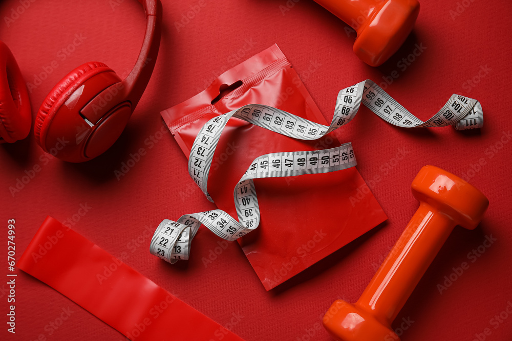 Composition with healthy snack, sports equipment and headphones on red background