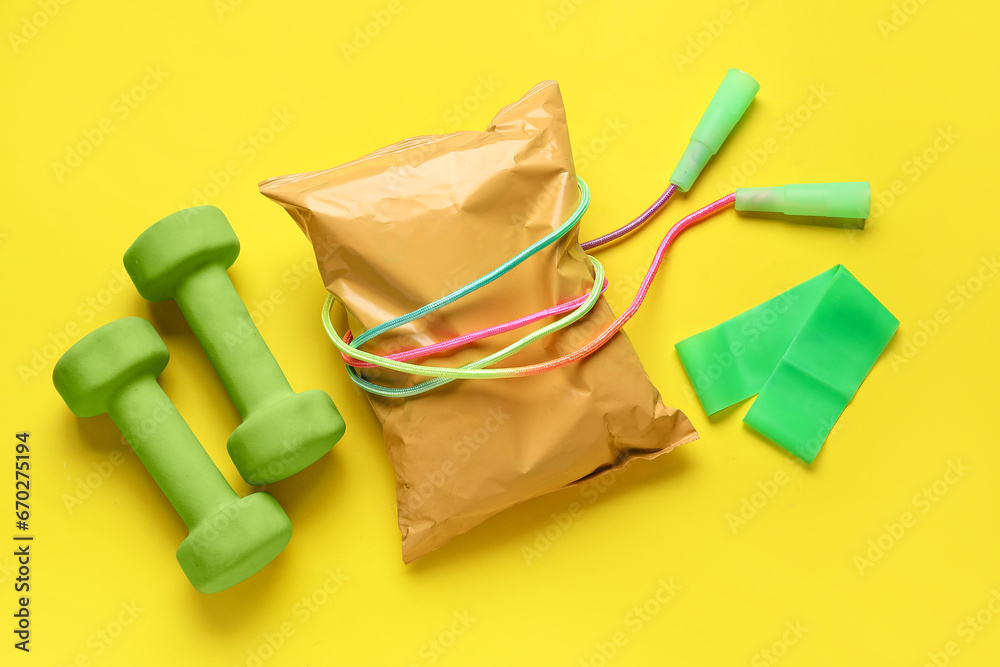 Healthy snack and sports equipment on yellow background