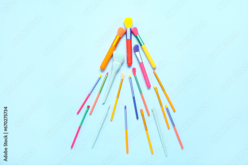 Christmas tree made of makeup brushes on blue background