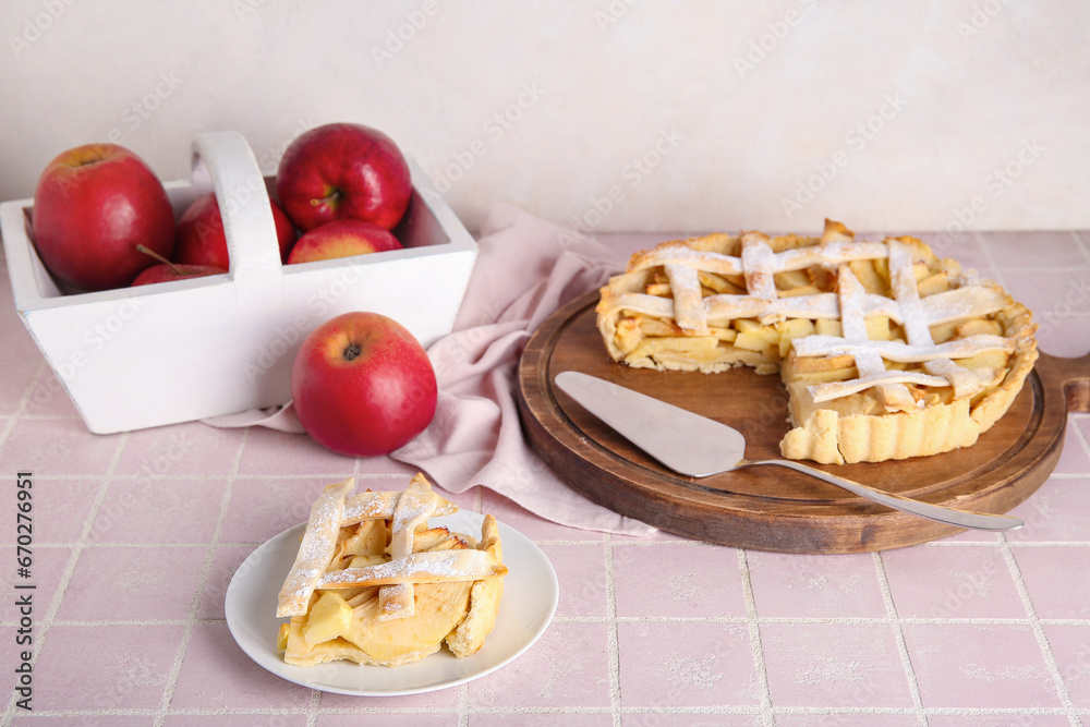 Wooden board and plate with delicious apple pie on pink tile table