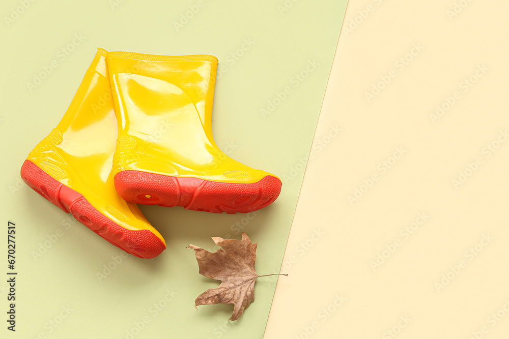 Yellow gumboots with autumn leaf on colorful background