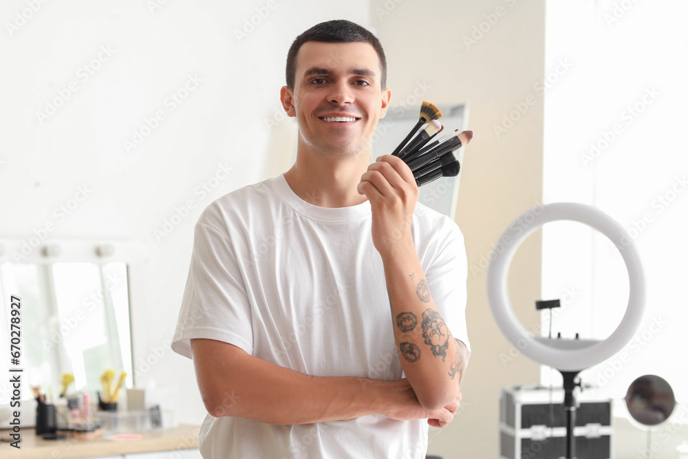 Male makeup artist with brushes in dressing room