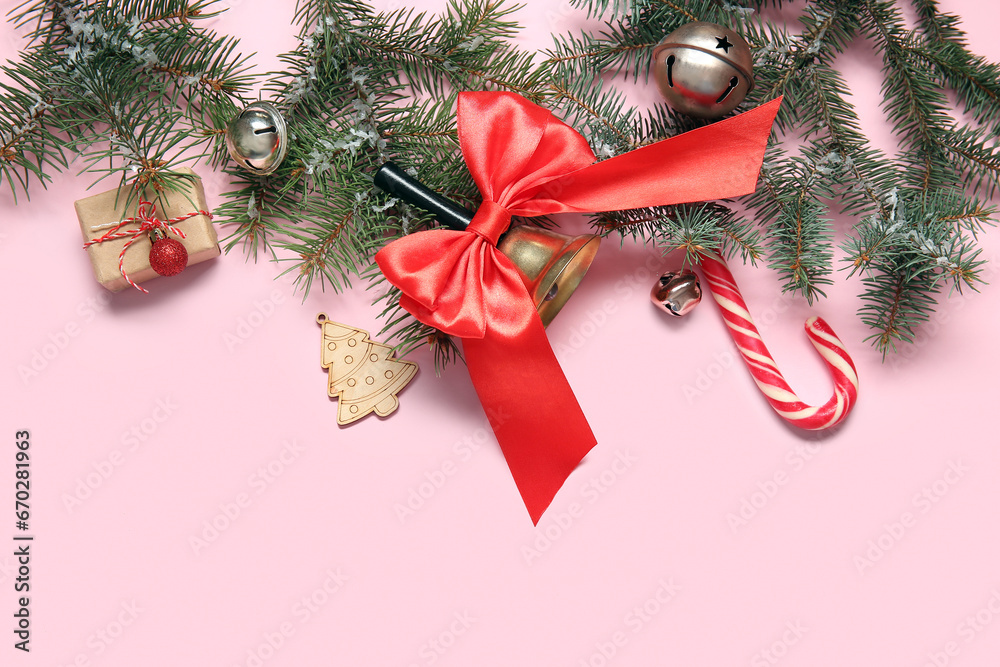 Christmas bell with fir branches, candy cane and balls on pink background