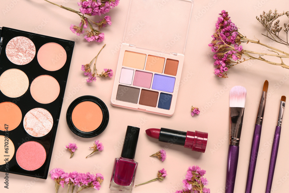 Composition with different makeup products and beautiful flowers on pink background