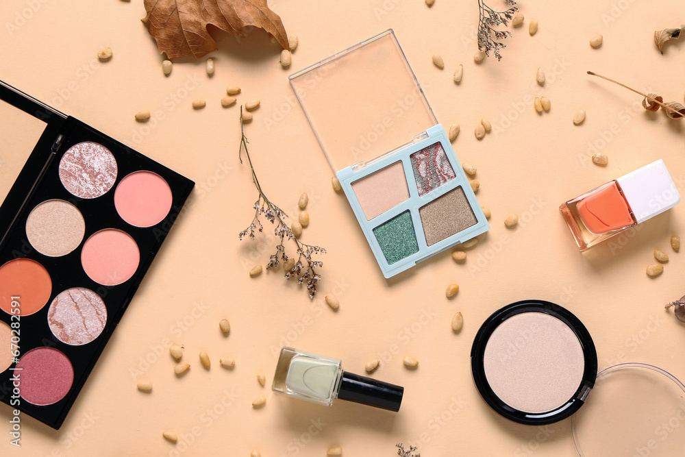 Composition with different makeup products and autumn decor on beige background