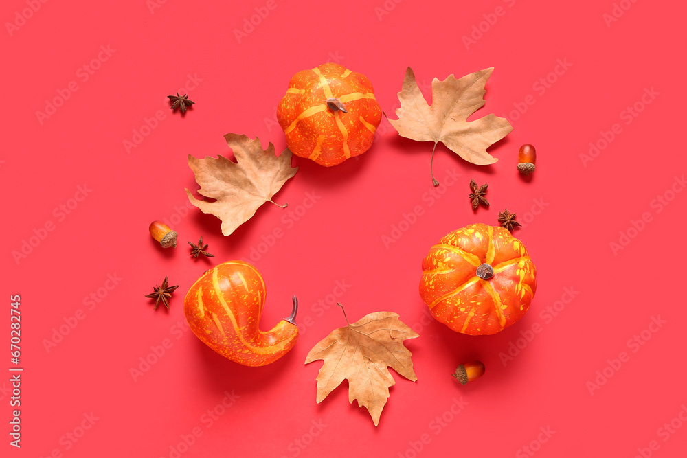 Frame made of ripe pumpkins, acorns, fallen leaves and spices on pink background