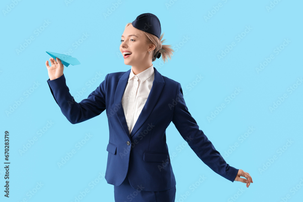 Young stewardess with paper plane on blue background