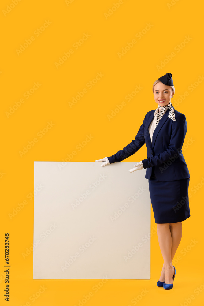 Young stewardess with blank poster on yellow background