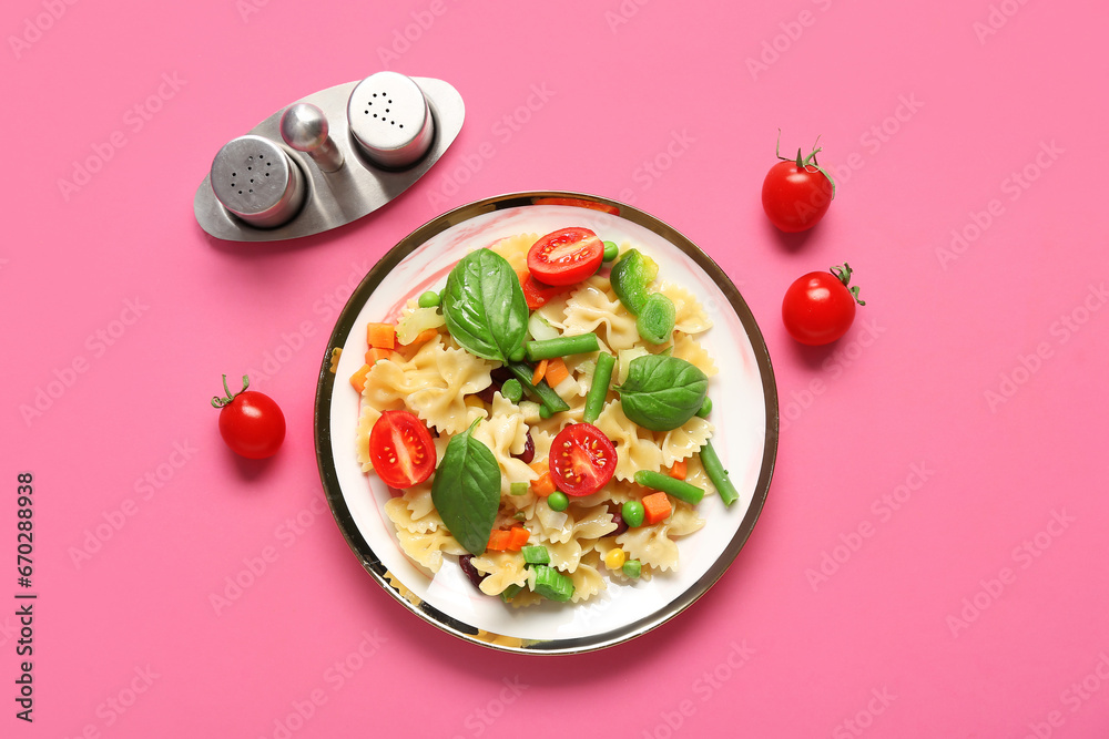 Plate with tasty pasta primavera on pink background