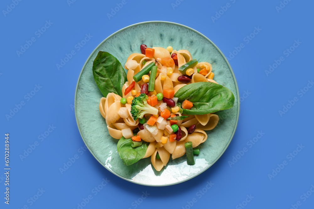 Plate with tasty pasta primavera on blue background