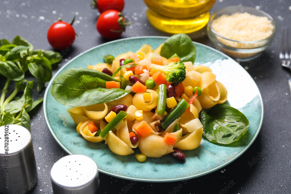 Plate with tasty pasta primavera on black background