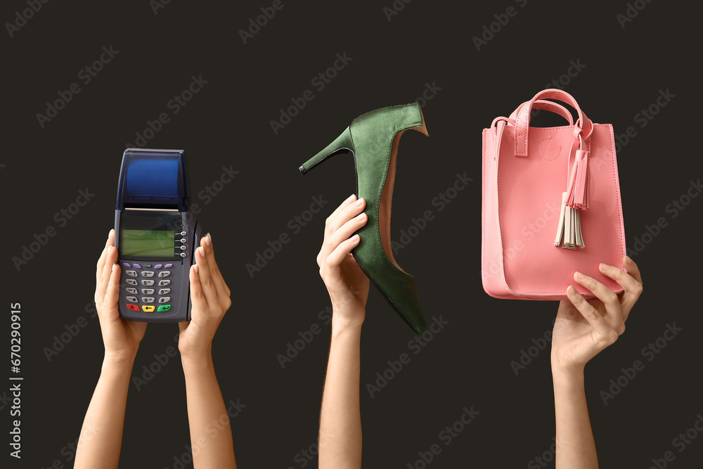 Female hands with payment terminal and women accessories on dark background. Black Friday sale