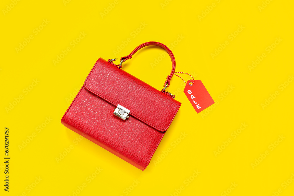 Stylish female handbag with sale tag on yellow background. Black Friday