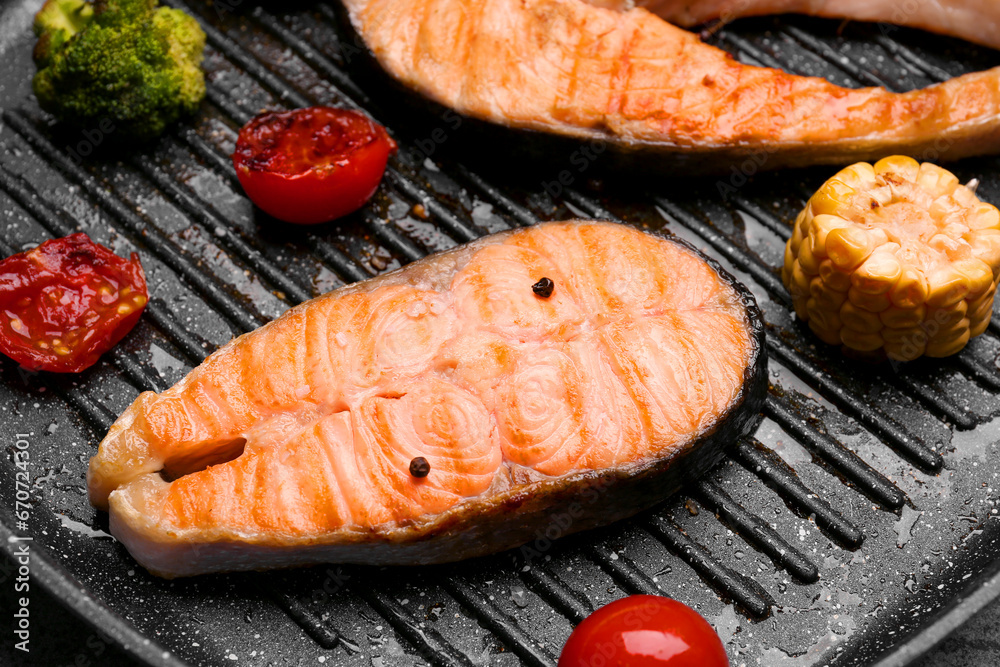 Tasty grilled salmon steaks and vegetables in frying pan, closeup