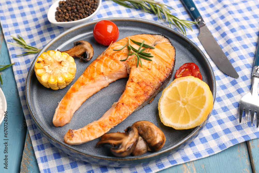 Plate with tasty grilled salmon steak on blue wooden background