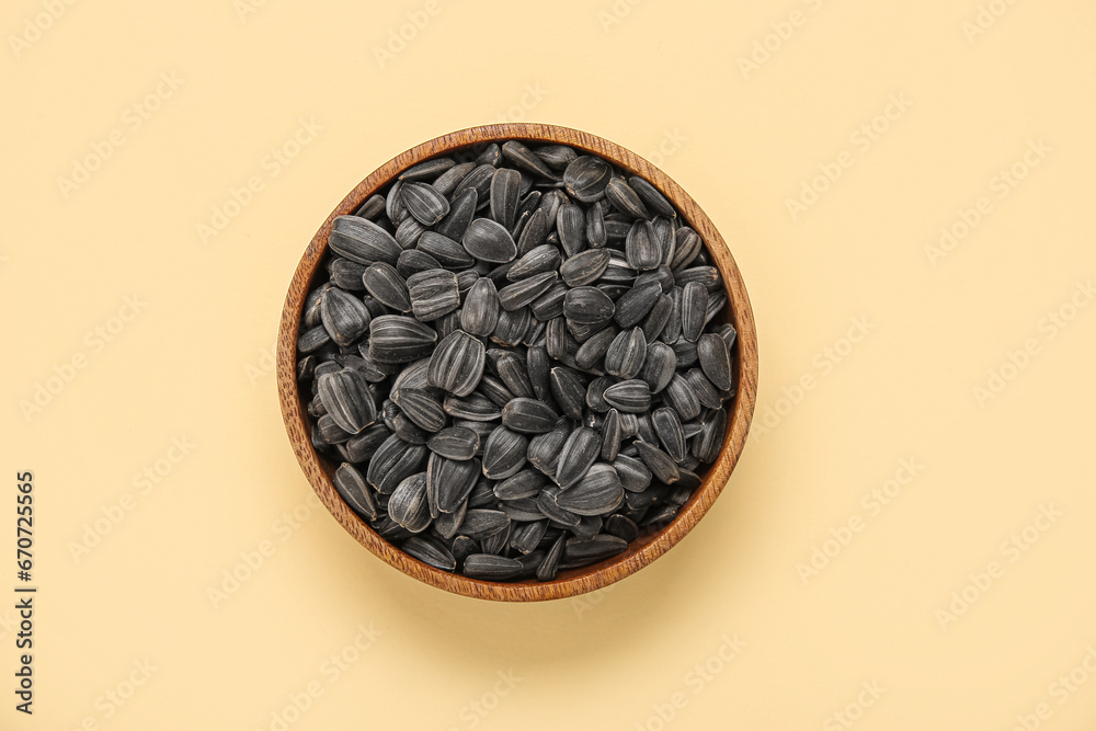 Bowl with sunflower seeds on yellow background