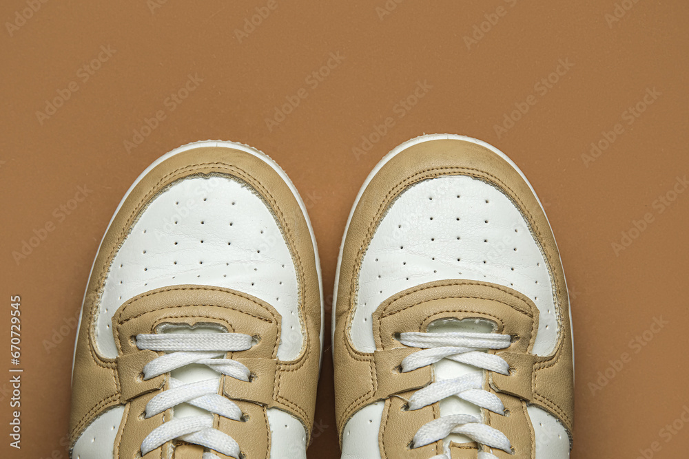 Stylish sneakers on brown background