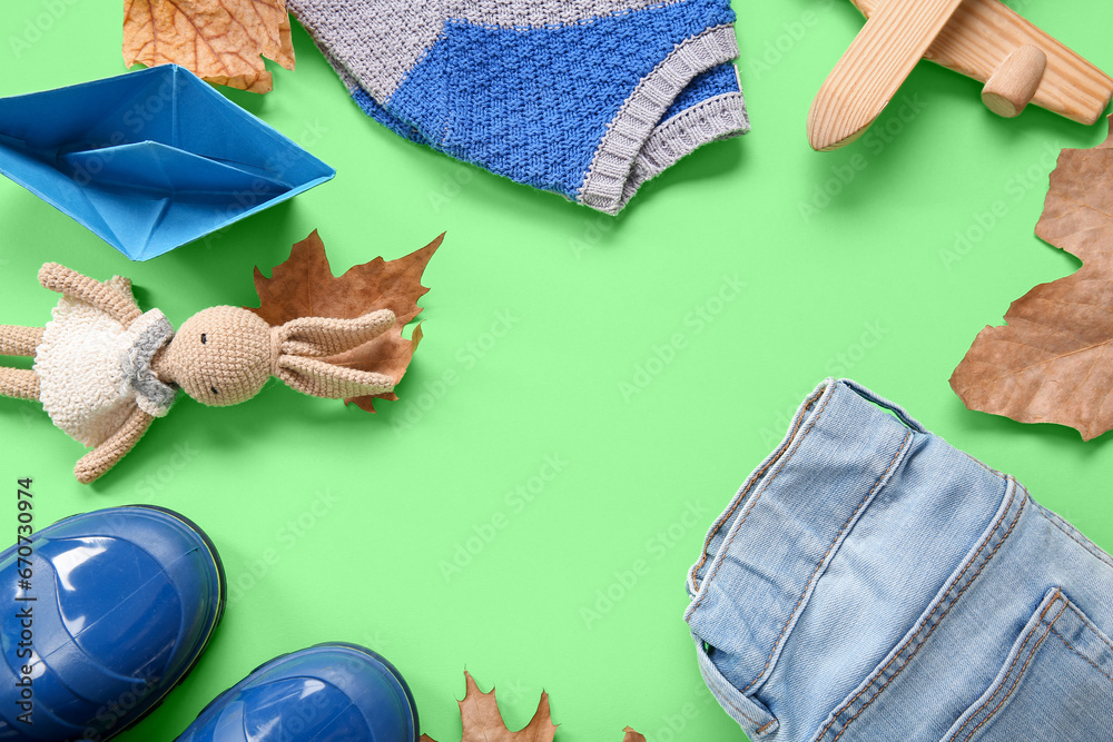 Frame made blue gumboots with autumn leaves, sweater and jeans on green background