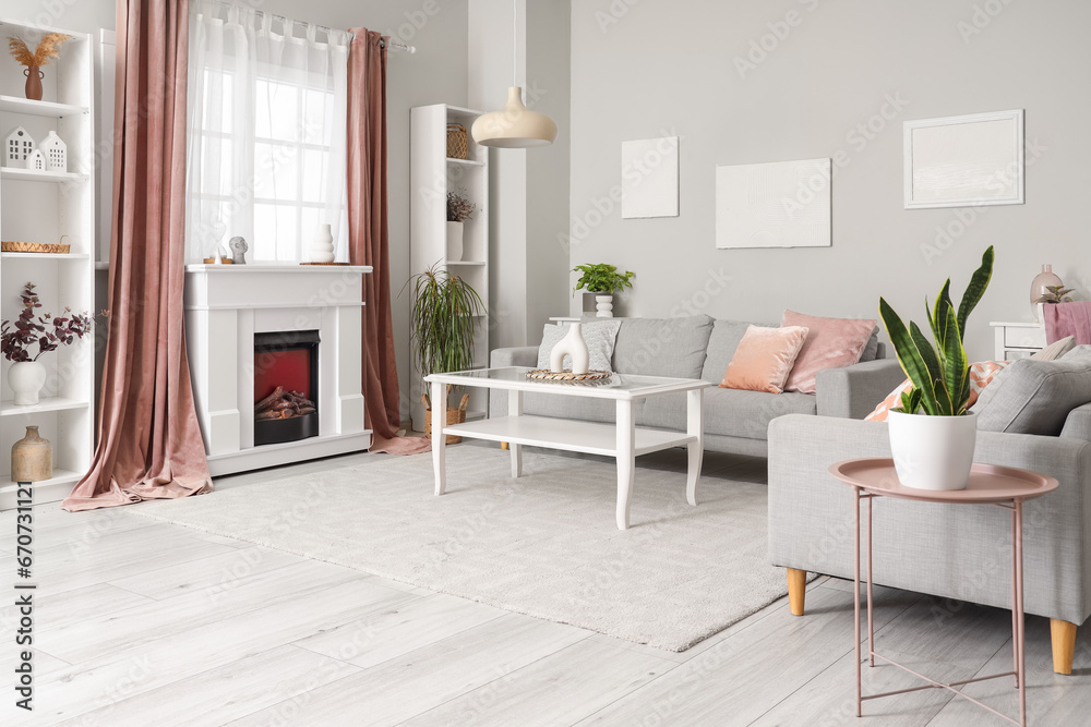 Interior of living room with modern fireplace, different home decorations and sofas