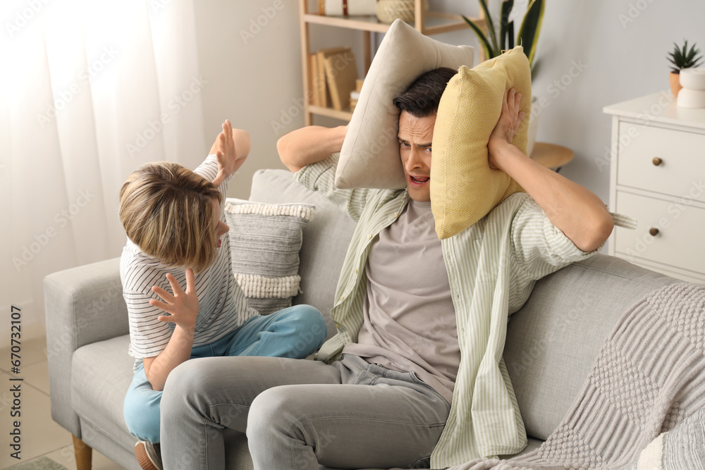 Young man with pillows stressed of his noisy son at home