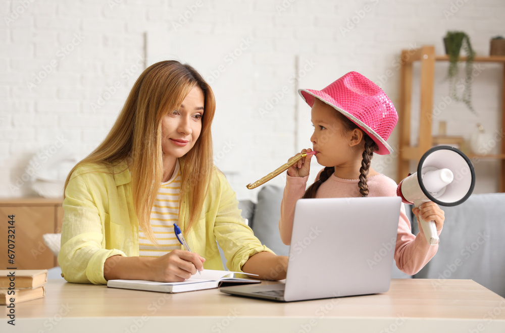 Working young woman stressed of her noisy little daughter at home