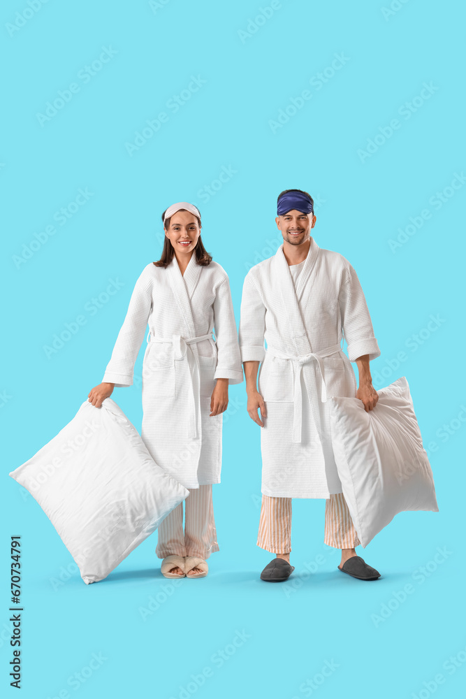 Young couple with soft pillows on blue background