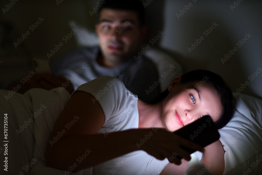 Young woman using mobile phone in bedroom at night, closeup