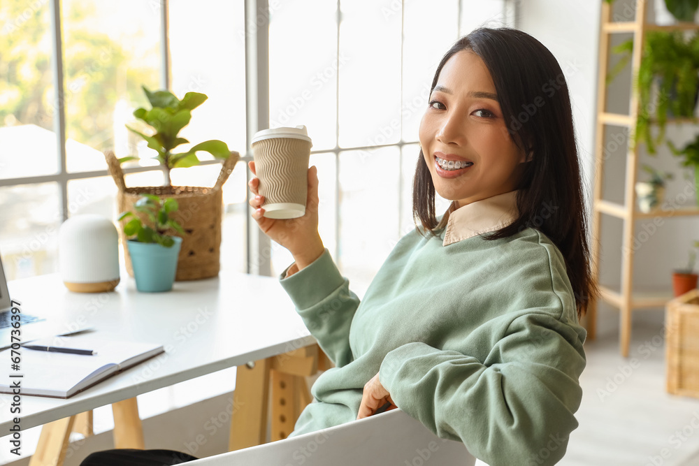 Young Asian woman with coffee cup at home office