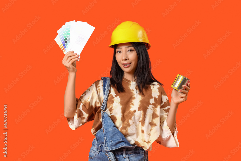 Young Asian woman with paint color palettes and can on orange background