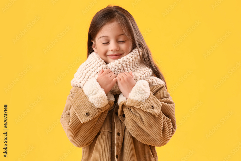 Little girl in winter clothes on yellow background