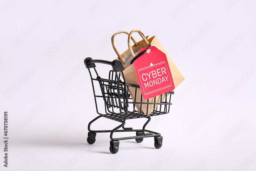 Small shopping cart with bag and tag on light background. Cyber Monday concept