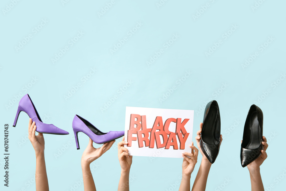 Female hands holding poster with text BLACK FRIDAY and stylish shoes on blue background