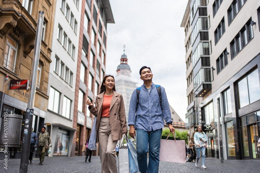 Asian young man and woman shopping goods outdoors in department store. 