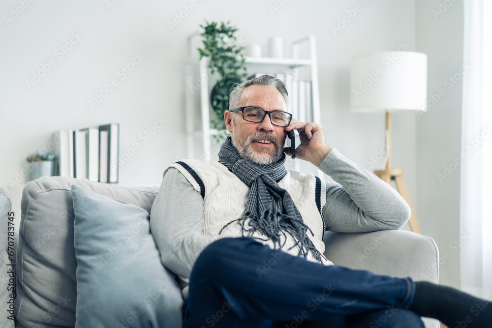 Caucasian senior elderly male using mobile phone in living room at home. 