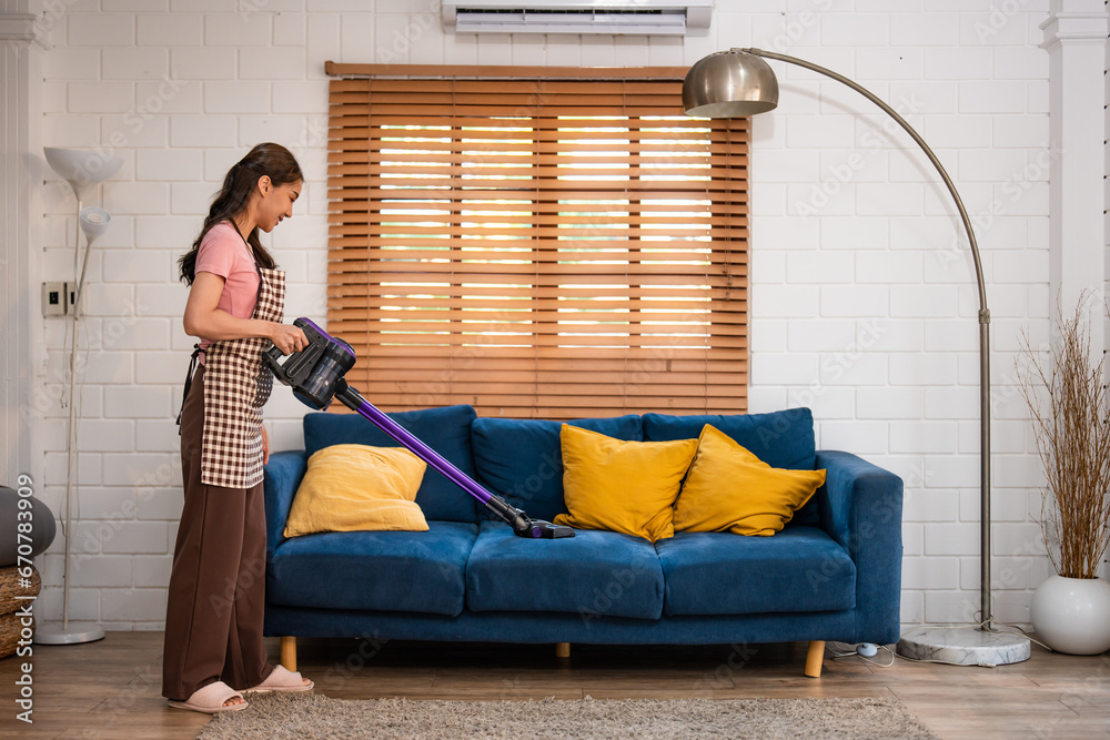 Asian young beautiful woman cleaning indoors in living room at home.