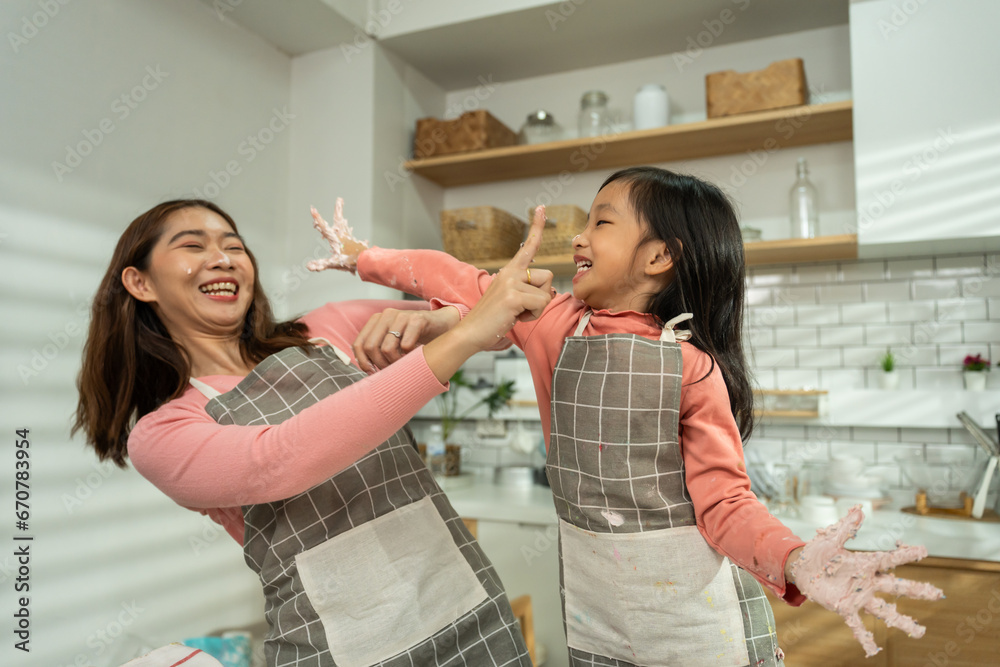 Asian attractive mother making cake with daughter in kitchen at house. 