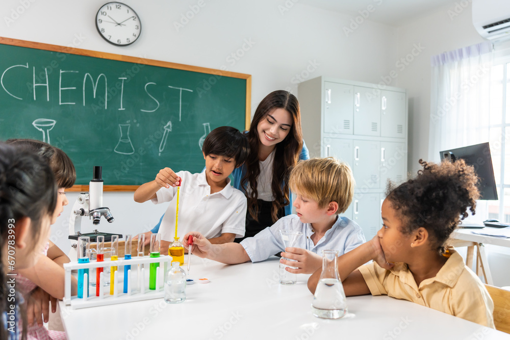 Adorable student learn with teacher in classroom at elementary school.