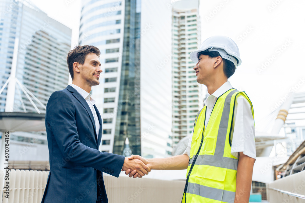 Caucasian businessman and Asian worker working in outdoors in city. 