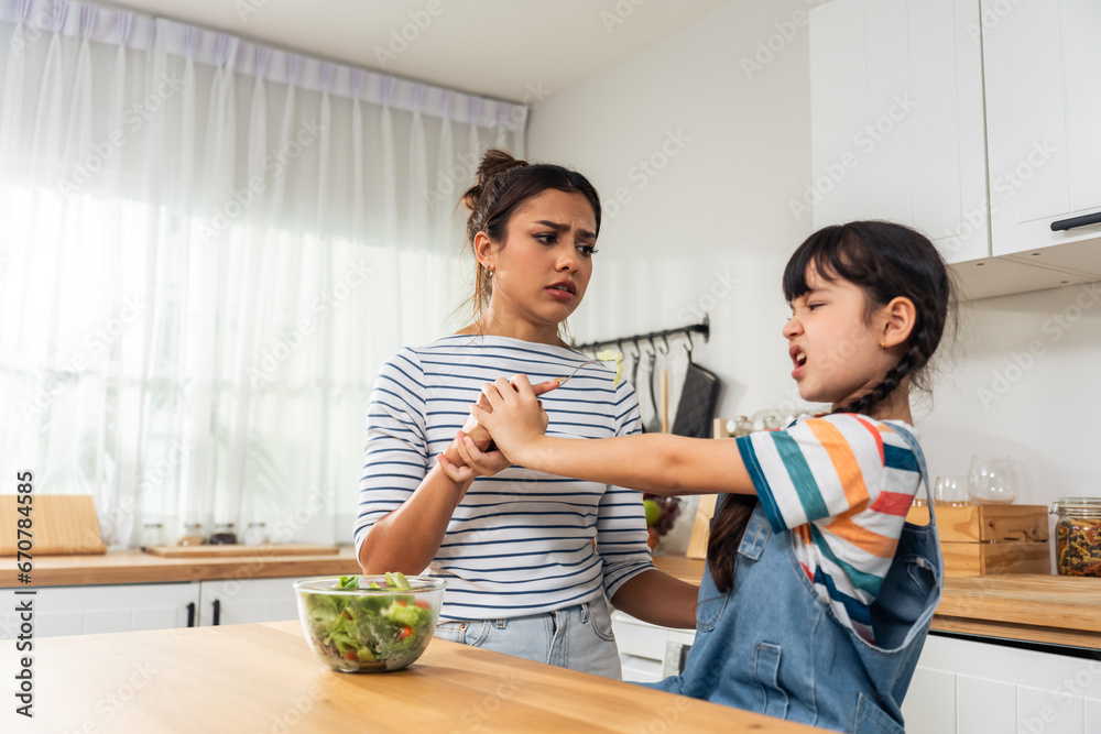 Caucasian mother teach and motivate young daughter eat green vegetable. 