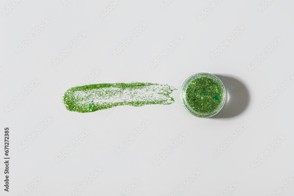 Jar of green glitter with stroke on grey background