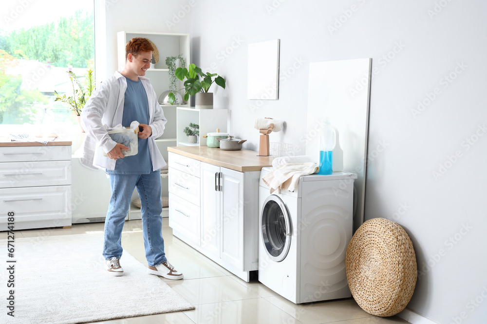 Young man with laundry basket near washing machine