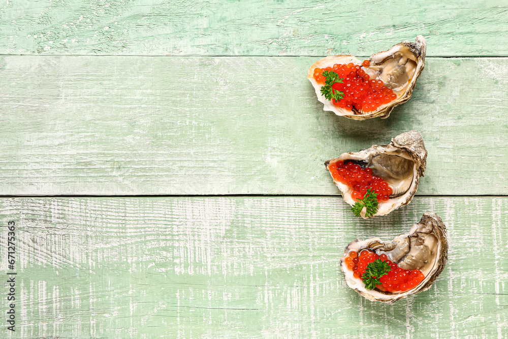 Tasty oysters with red caviar on green wooden background