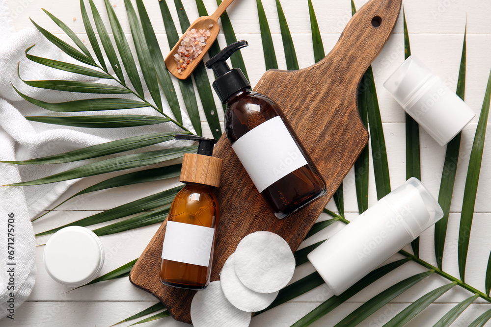 Bottles of shampoo and cosmetic products on white wooden background